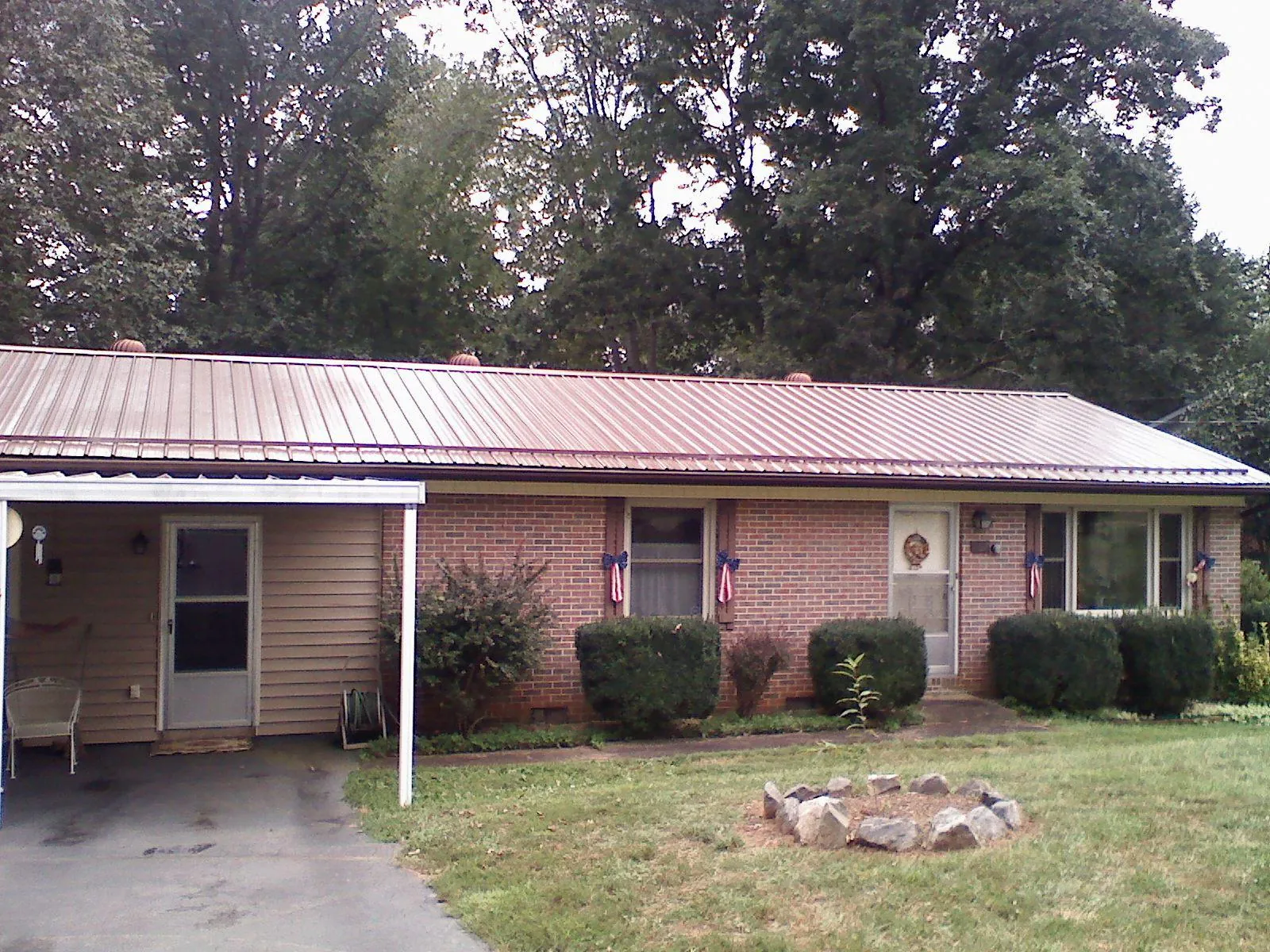 Bronze metal roof and carport on a brick ranch home — Roof Repair work by our crew in Liberty
