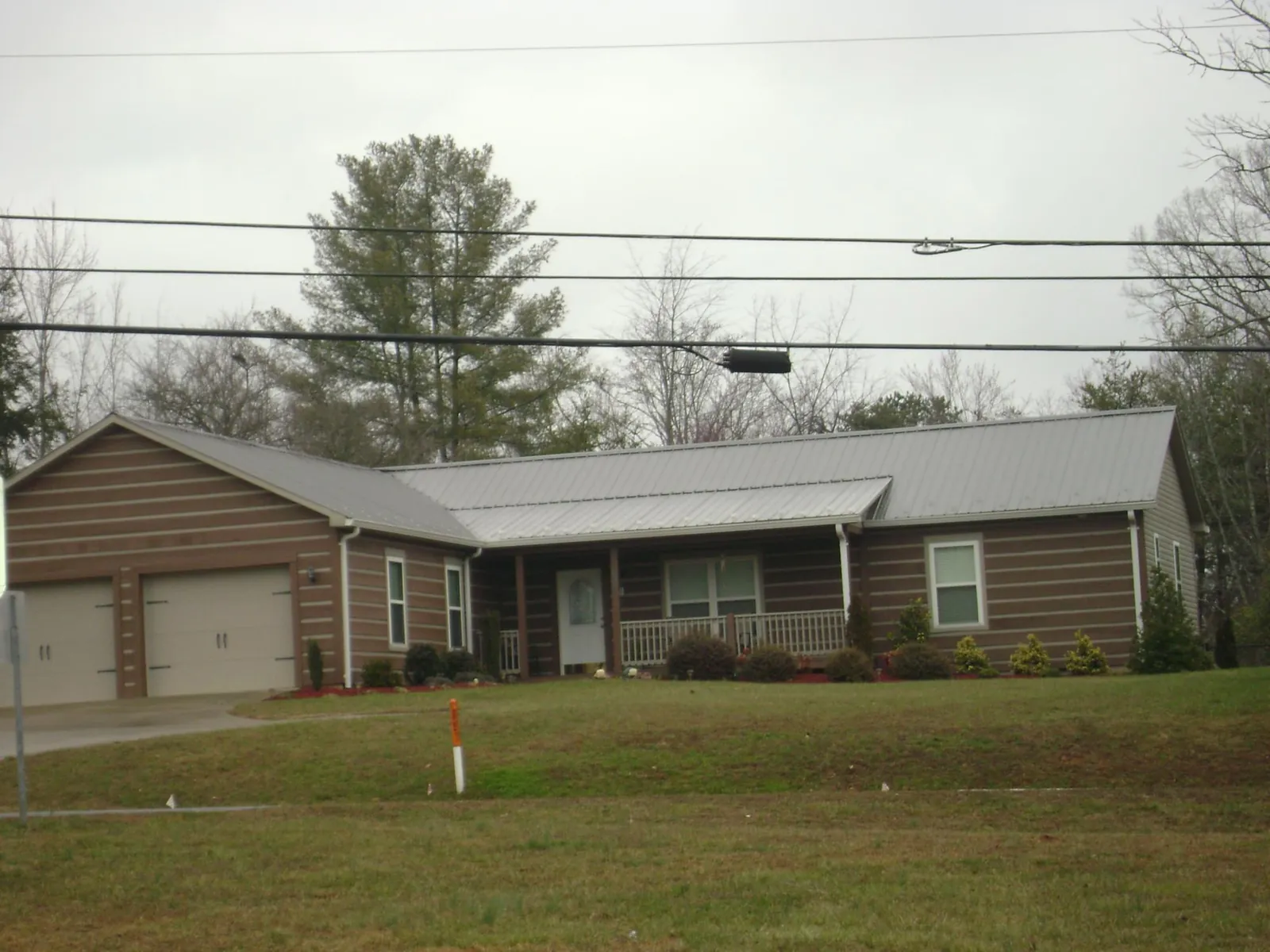 Gray metal roof on a log sided ranch home with a front porch in Liberty